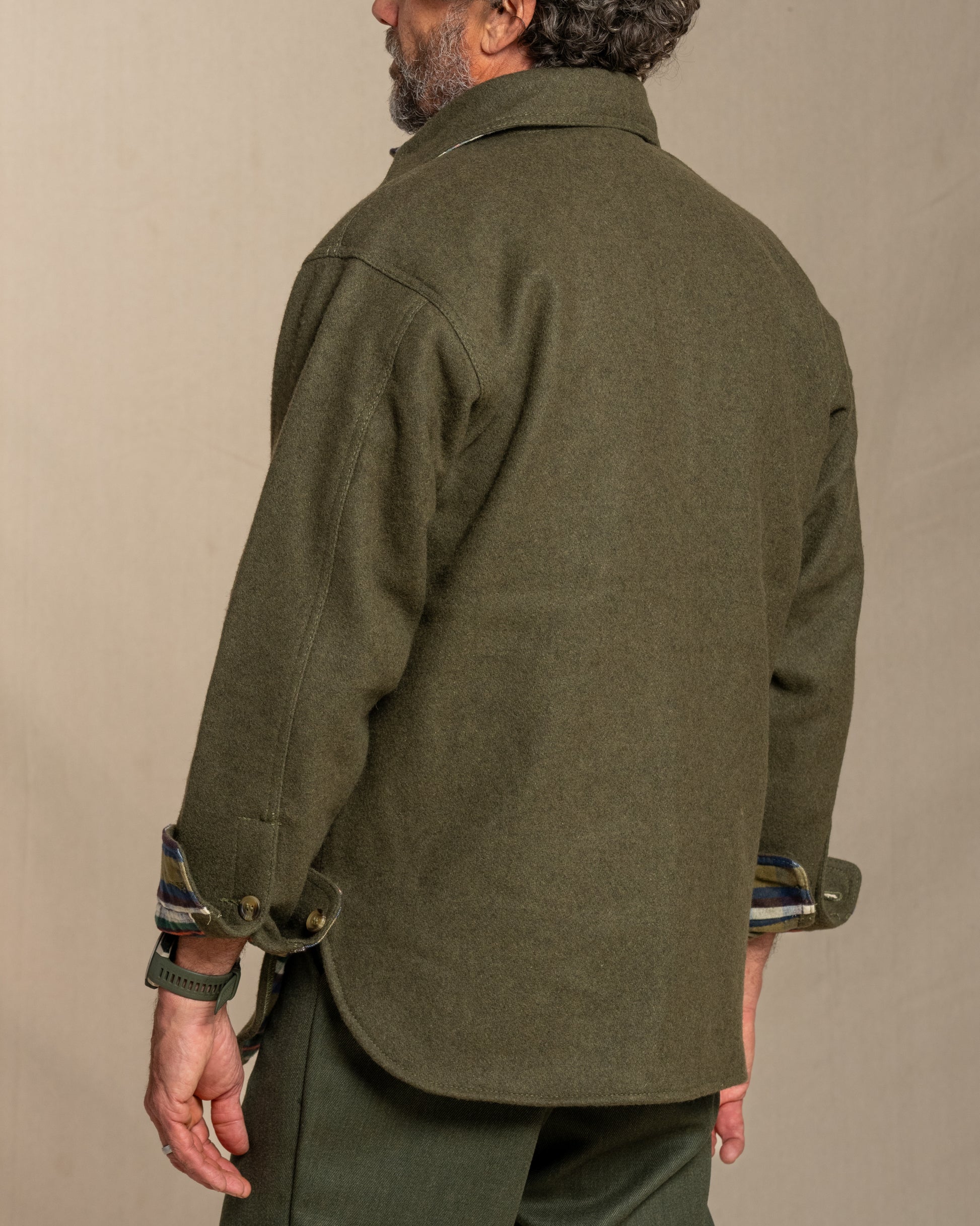 Man wearing a loden wool shirt with plaid flannel lining against a beige background