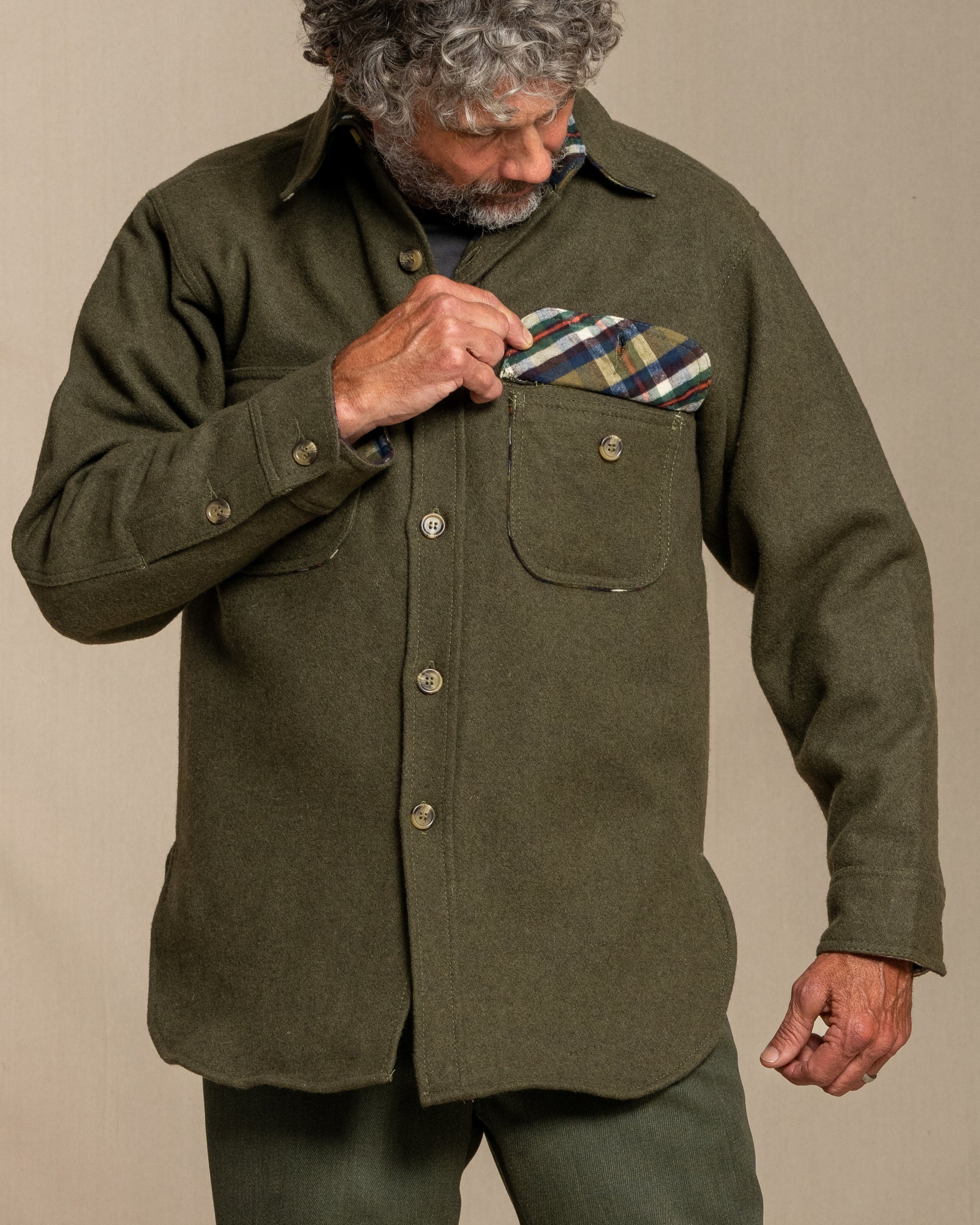 Man wearing a loden wool shirt with plaid flannel lining against a beige background