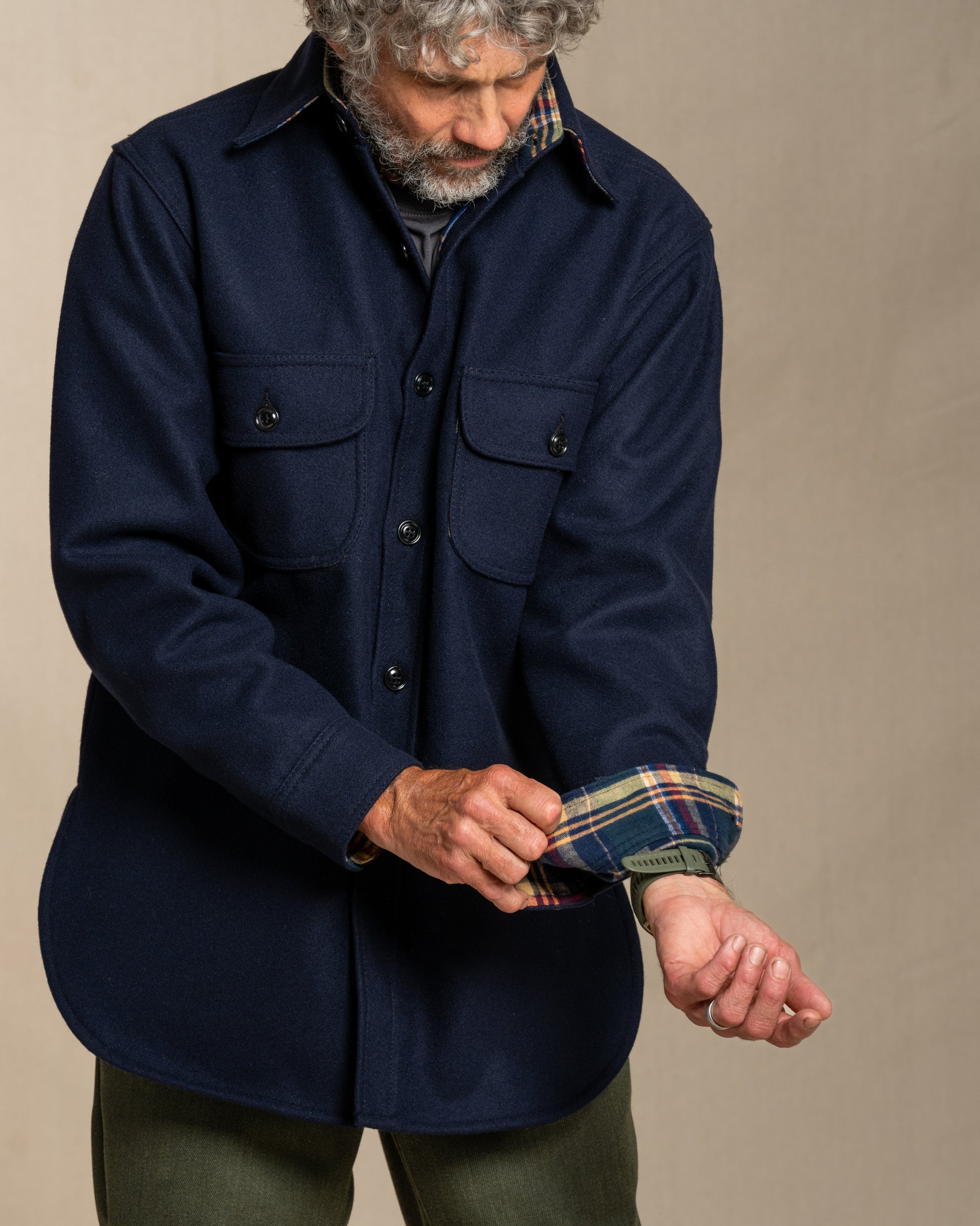 Man wearing a navy wool shirt with plaid flannel lining, standing against a canvas background