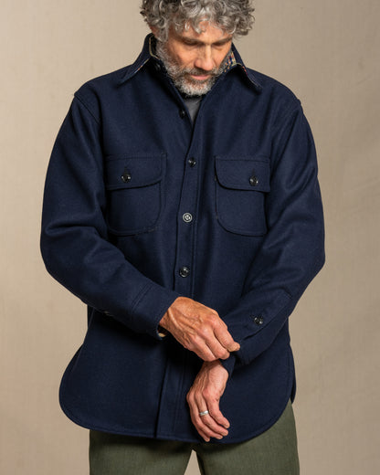 Man wearing a navy wool shirt, standing against a canvas background