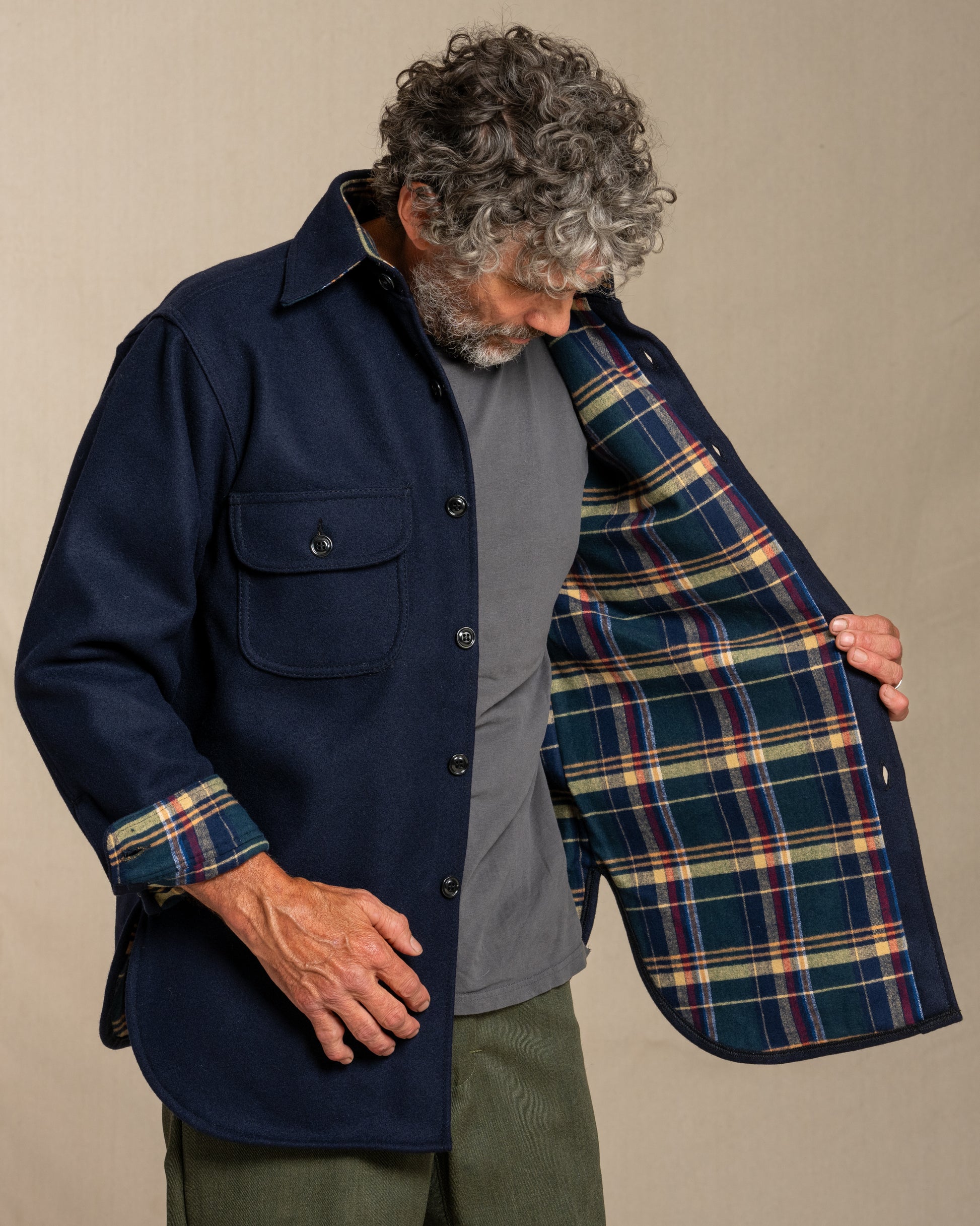 Man wearing a navy wool shirt with plaid flannel lining, standing against a canvas background
