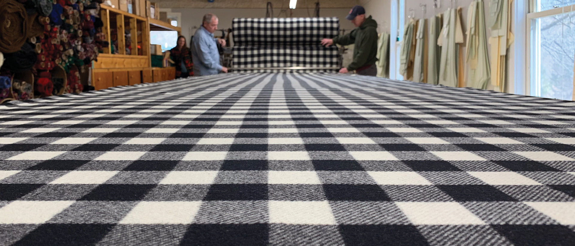 black and white buffalo check fabric on a large table with people working in the background