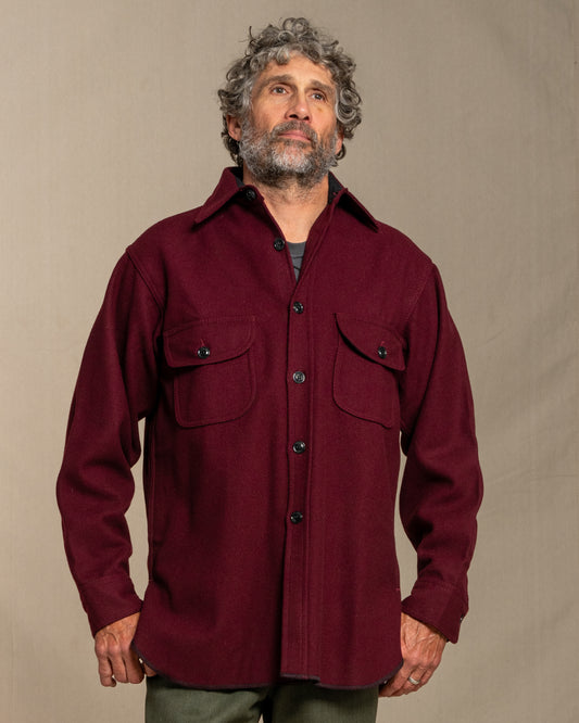 Man wearing a burgundy wool shirt against a beige background