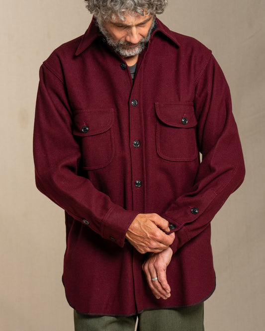 Man wearing a burgundy wool shirt against a beige background