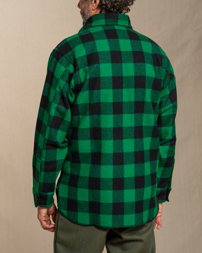Man wearing a green and black checkered wool shirt against a beige background