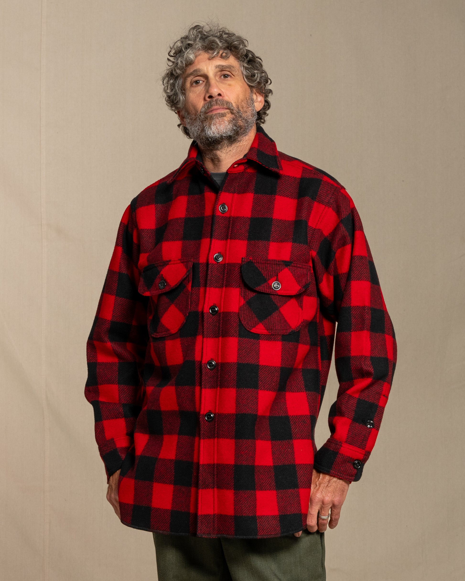 Man wearing a red and black checkered wool shirt against a beige background