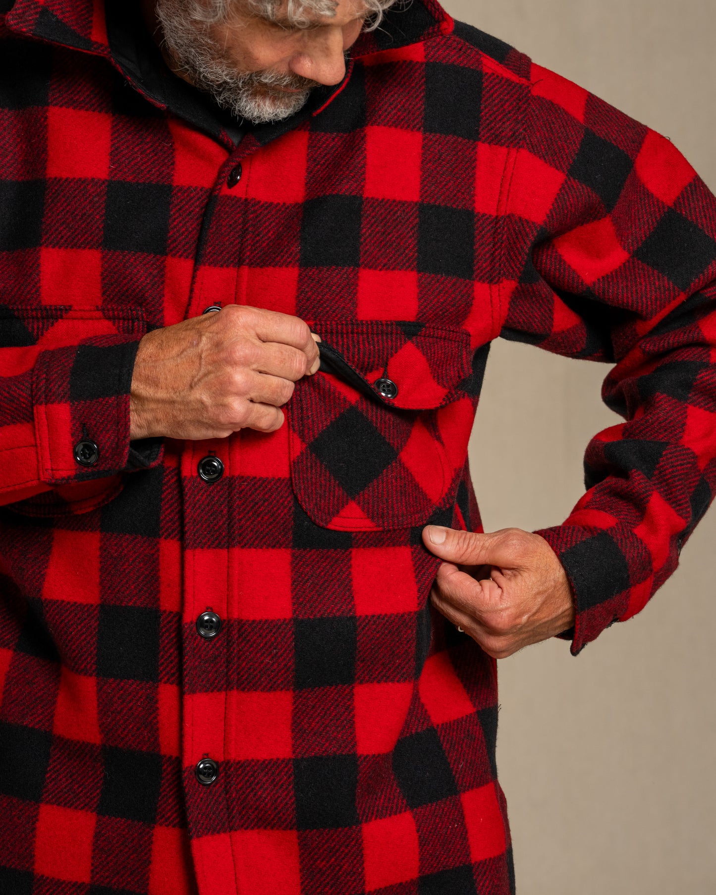 Man wearing a red and black checkered wool shirt against a beige background