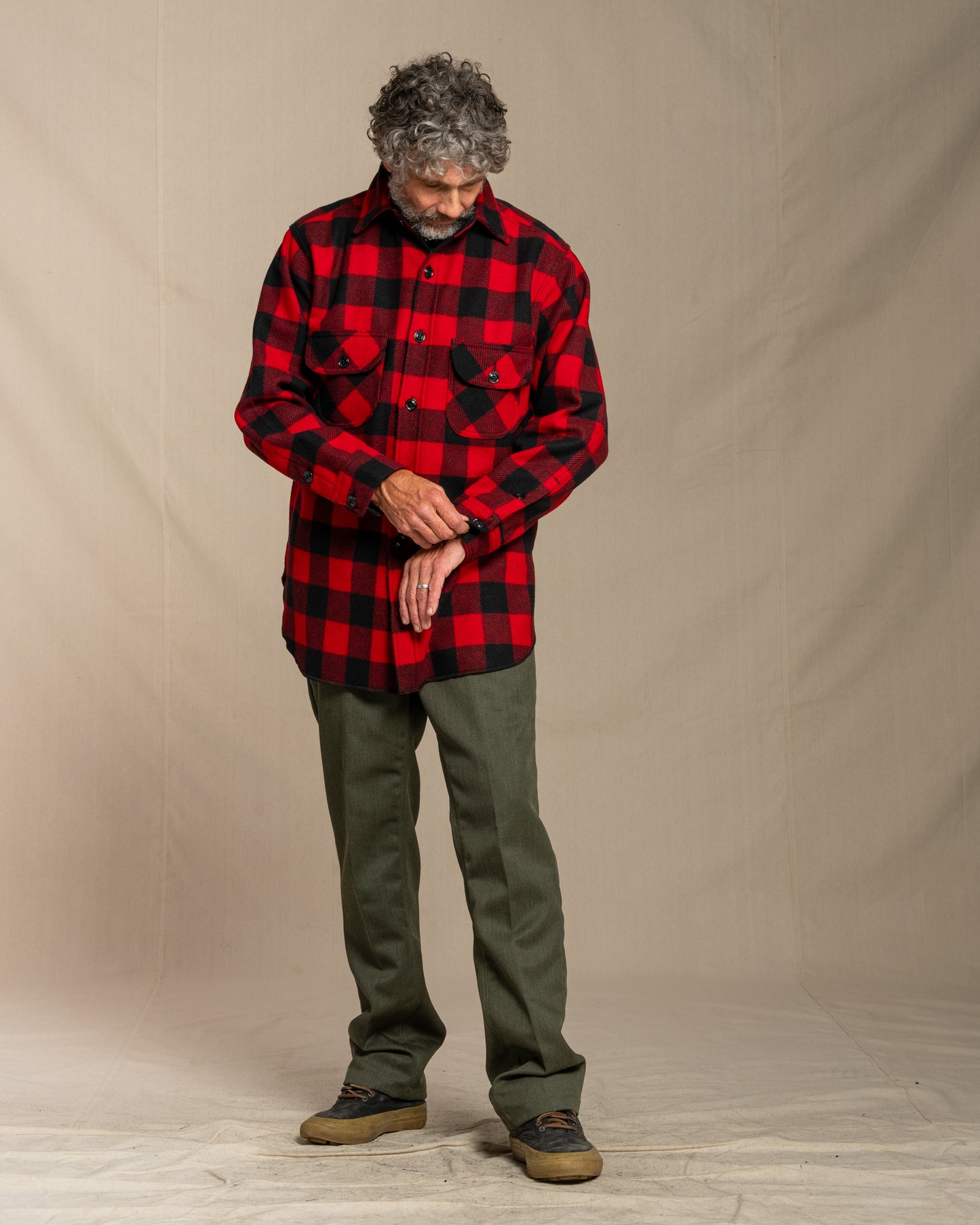 Man wearing a red and black checkered wool shirt against a beige background