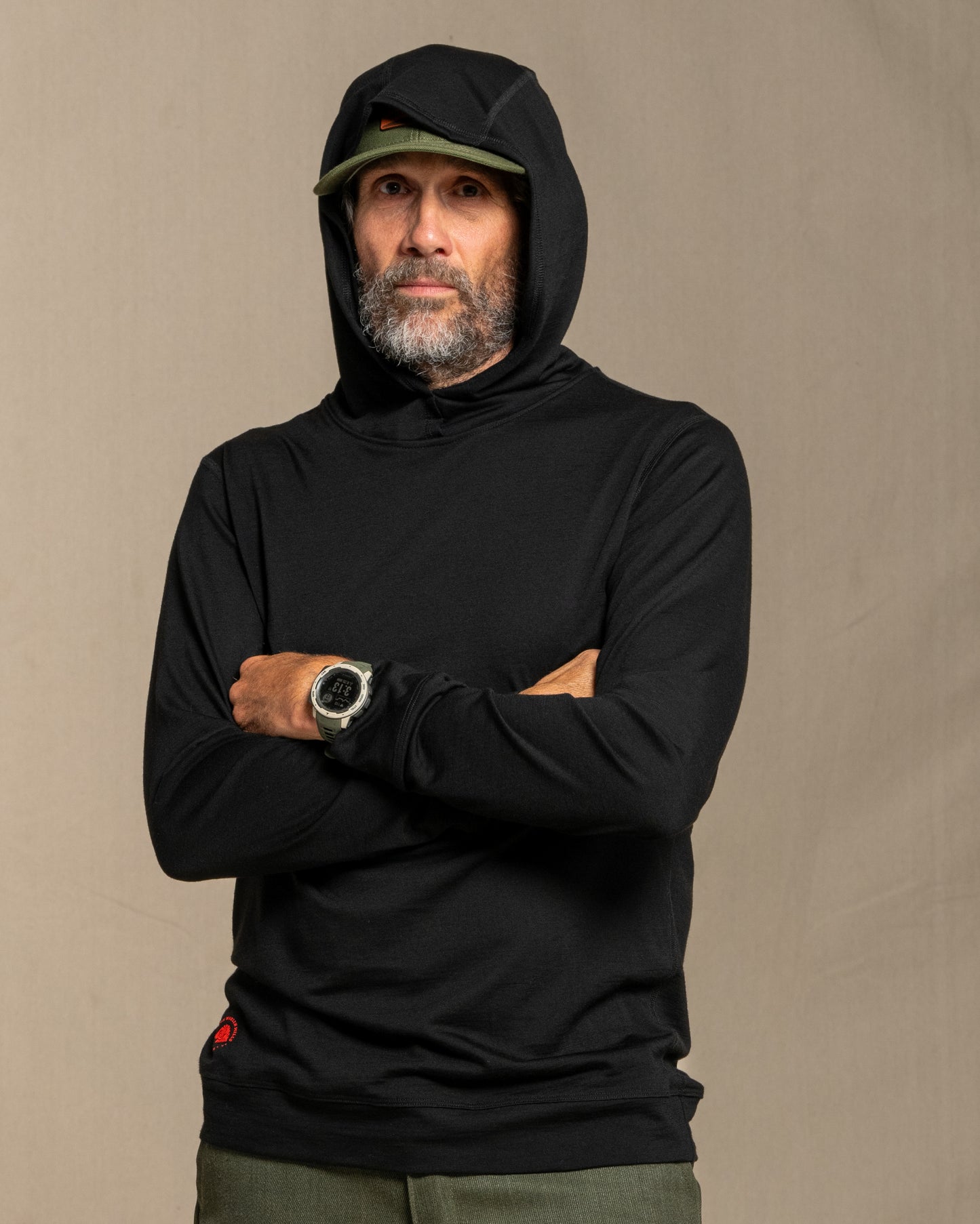Man wearing a black merino wool hoodie against a beige background