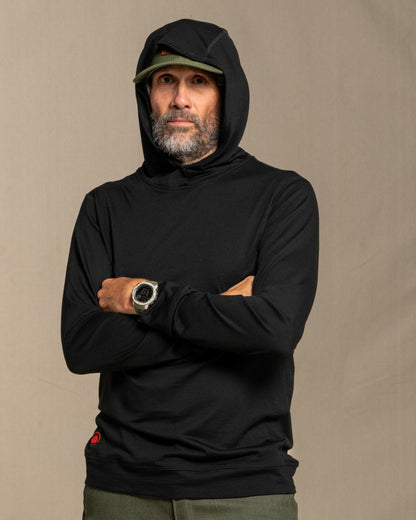 Man wearing a black merino wool hoodie against a beige background