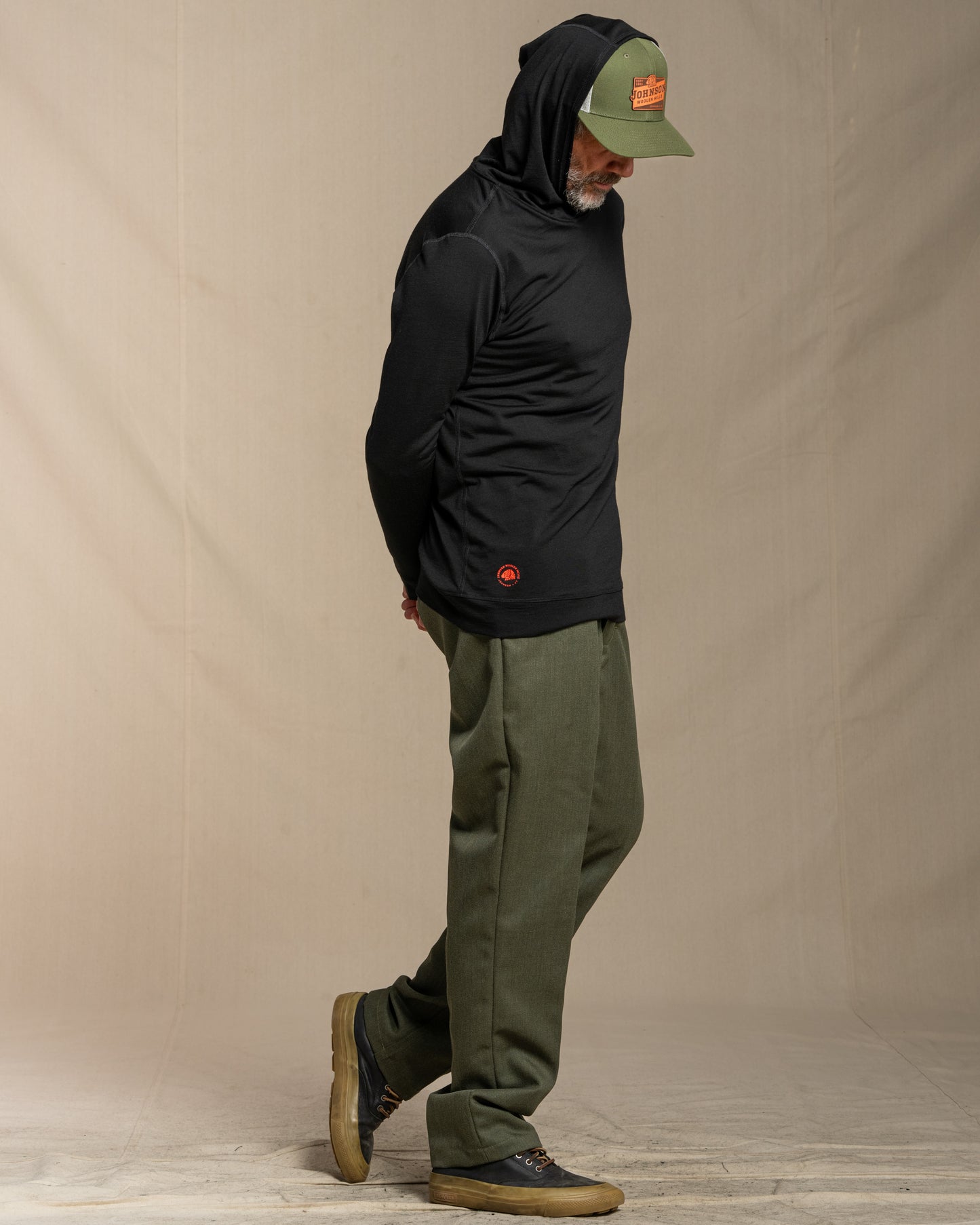 Man wearing a black merino wool hoodie against a beige background