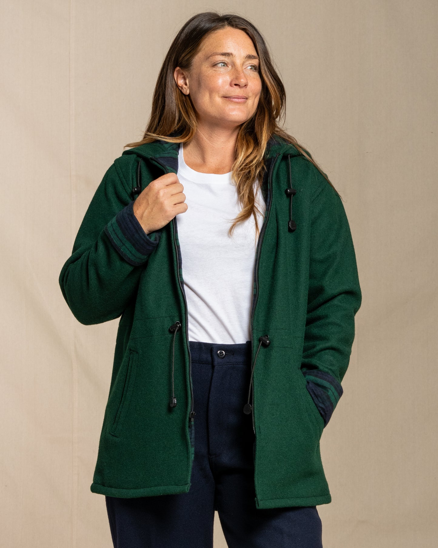 Woman wearing a green wool jacket with a beige background