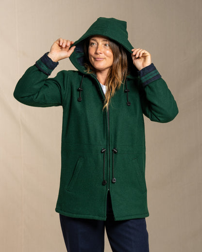 Person wearing a green hooded wool coat against a beige background