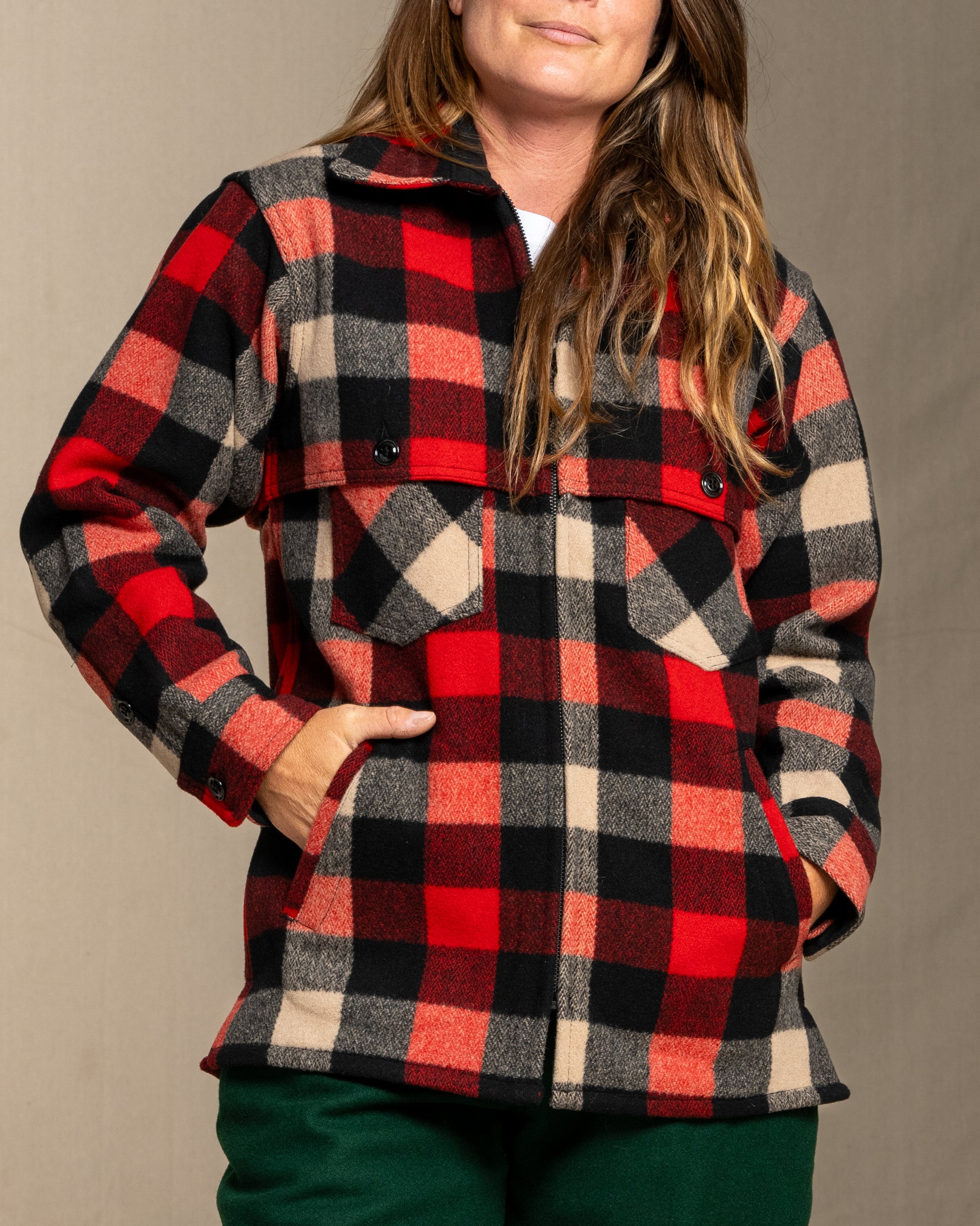 Person wearing a wool red and black and beige plaid jacket against a neutral background