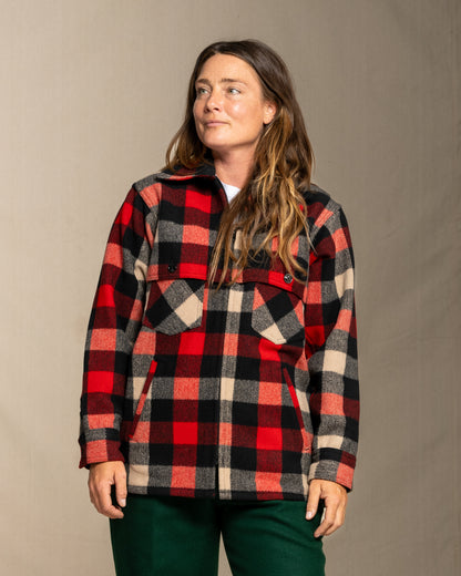 Person wearing a wool red and black and beige plaid jacket against a neutral background