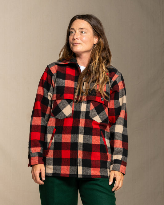 Person wearing a wool red and black and beige plaid jacket against a neutral background