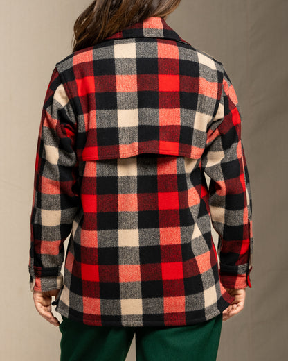 Person wearing a wool red and black and beige plaid jacket against a neutral background