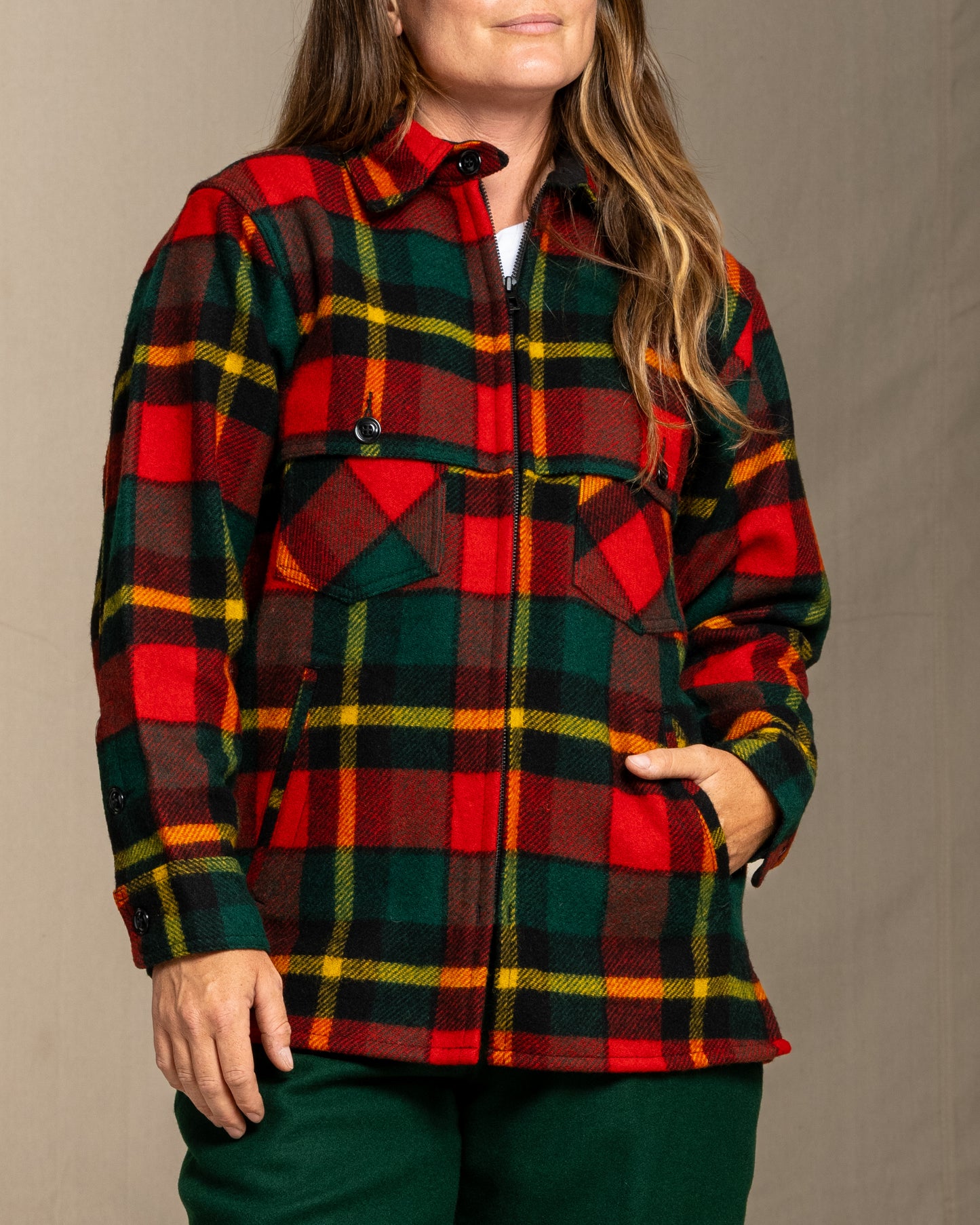 Woman wearing a red green and yellow plaid wool jacket against a neutral background