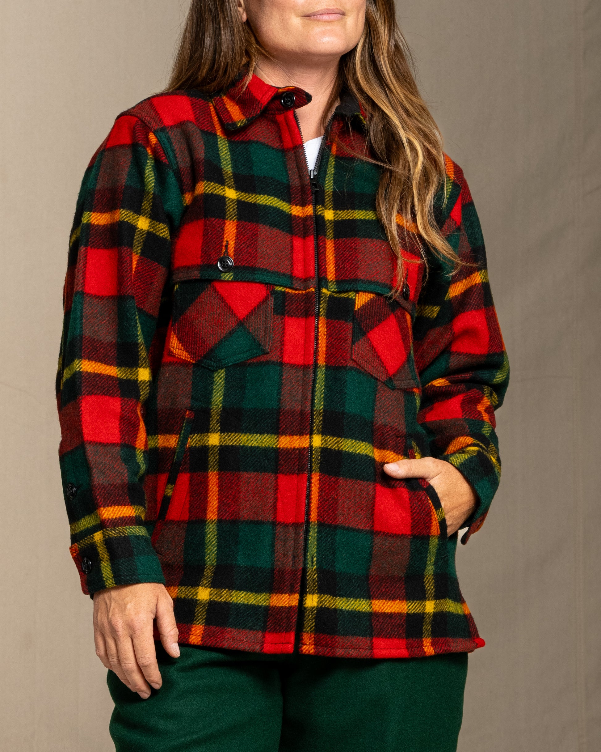 Woman wearing a red green and yellow plaid wool jacket against a neutral background