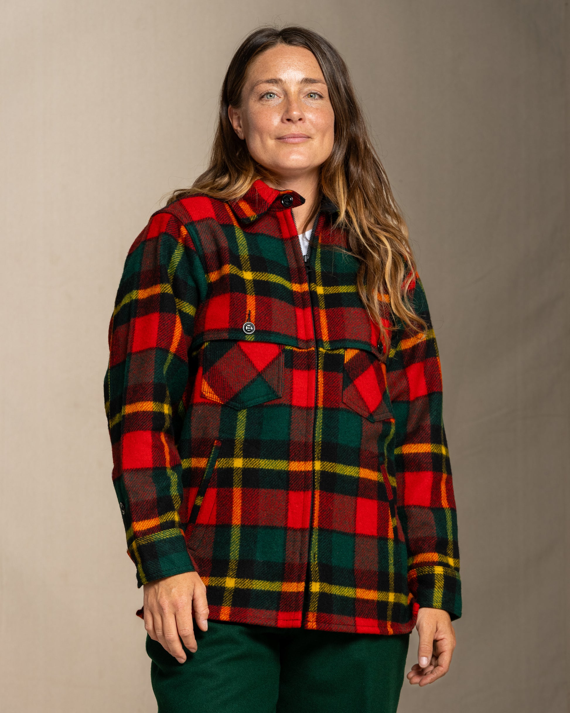 Woman wearing a red green and yellow plaid wool jacket against a neutral background