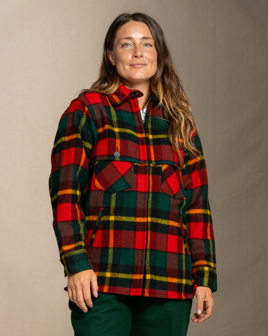 Woman wearing a red green and yellow plaid wool jacket against a neutral background