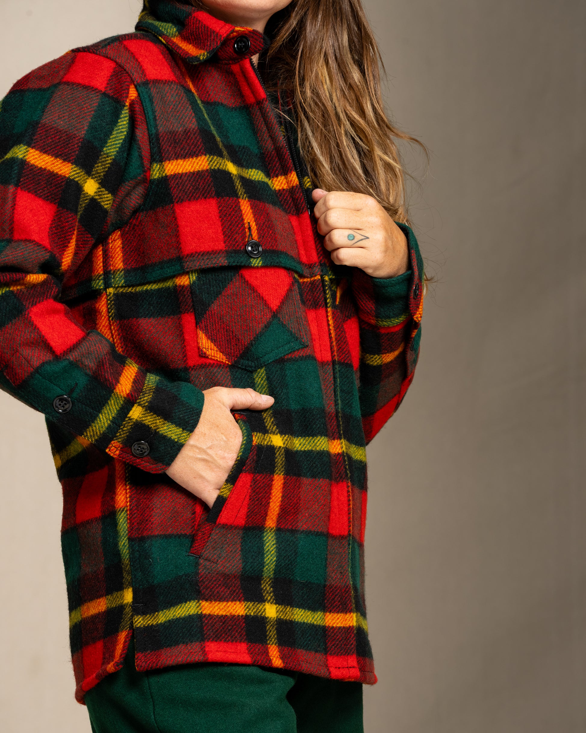 Woman wearing a red green and yellow plaid wool jacket against a neutral background
