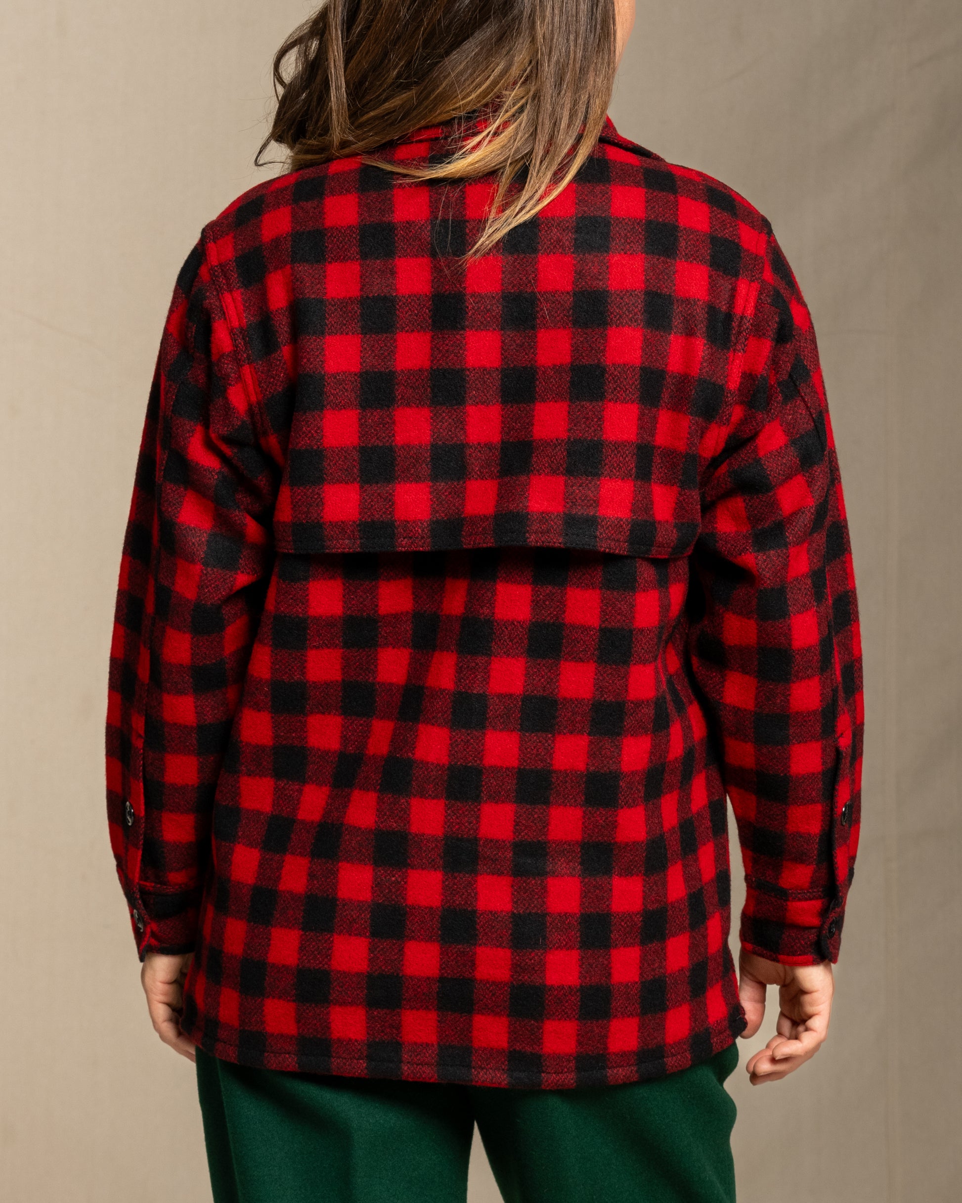 Person wearing a wool red and black jac shirt shirt against a neutral 