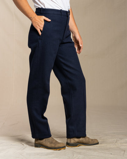 Person wearing navy wool pants on a beige background
