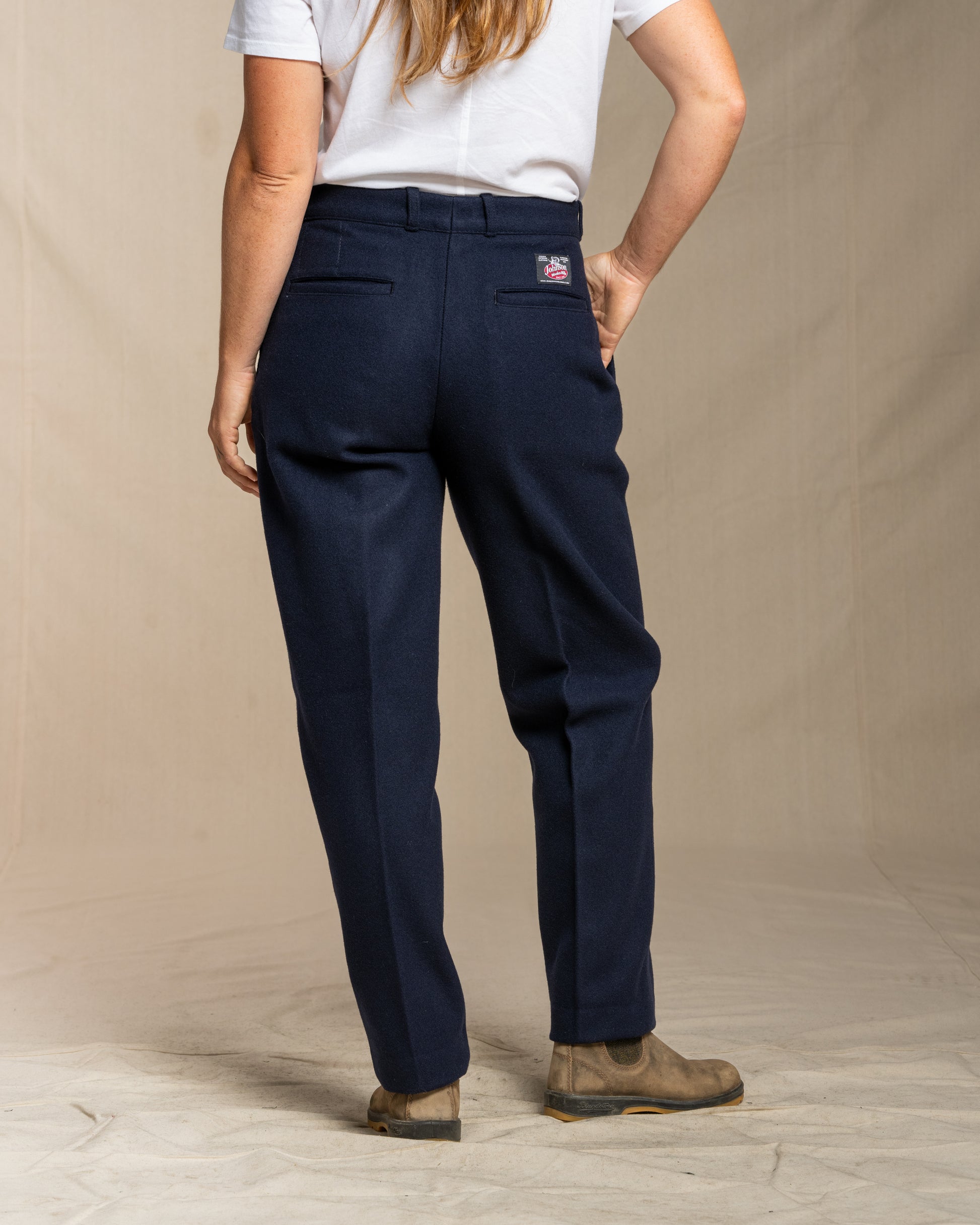 Person wearing navy wool pants on a beige background