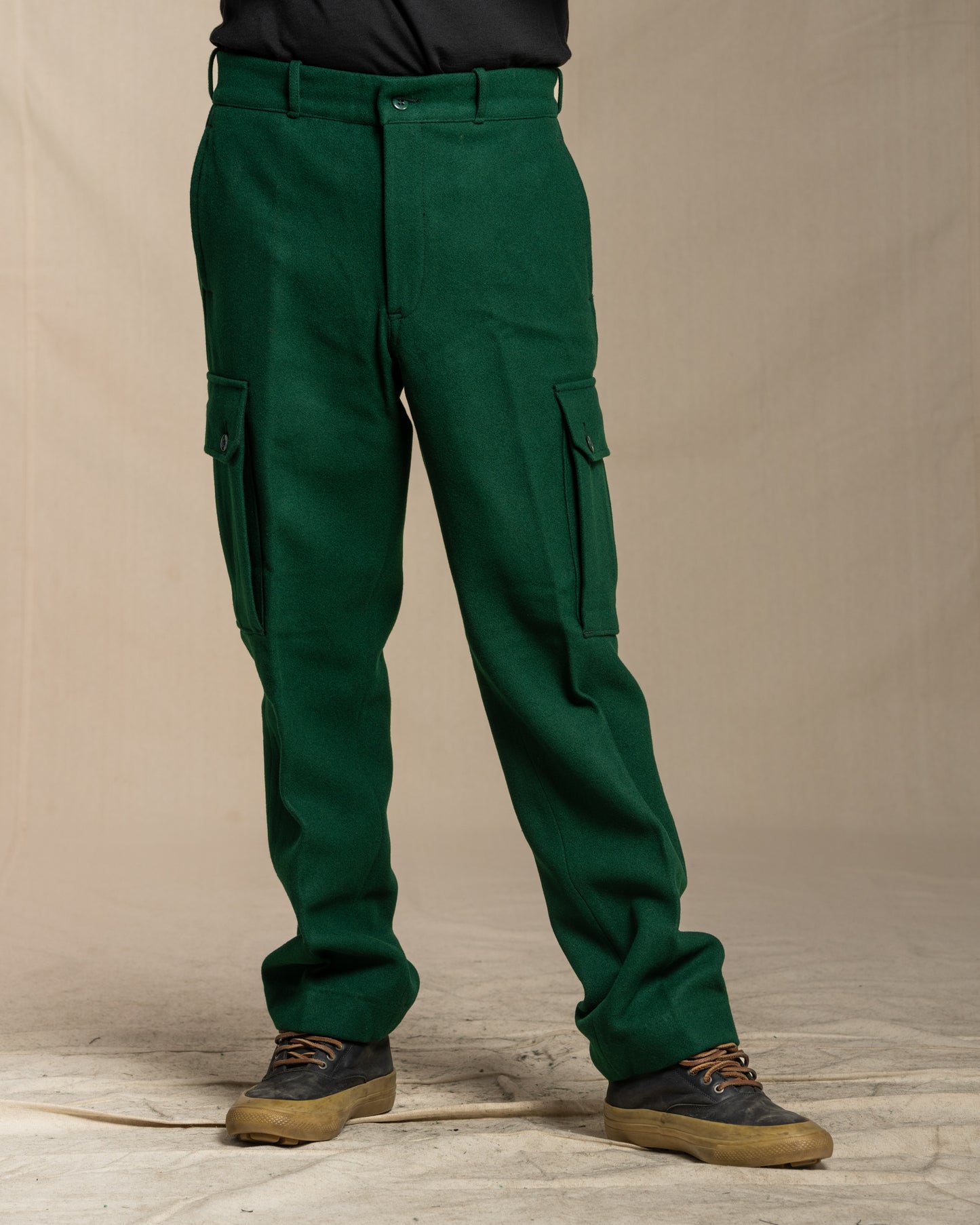 Green wool cargo pants worn by a person on a canvas background