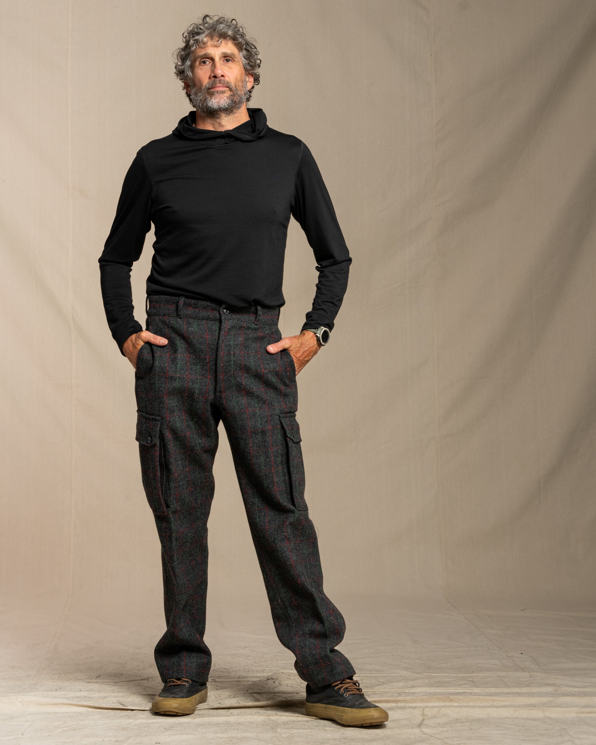 Man wearing a black merino wool hoodie and Adirondack plaid wool cargo pants against a canvas background