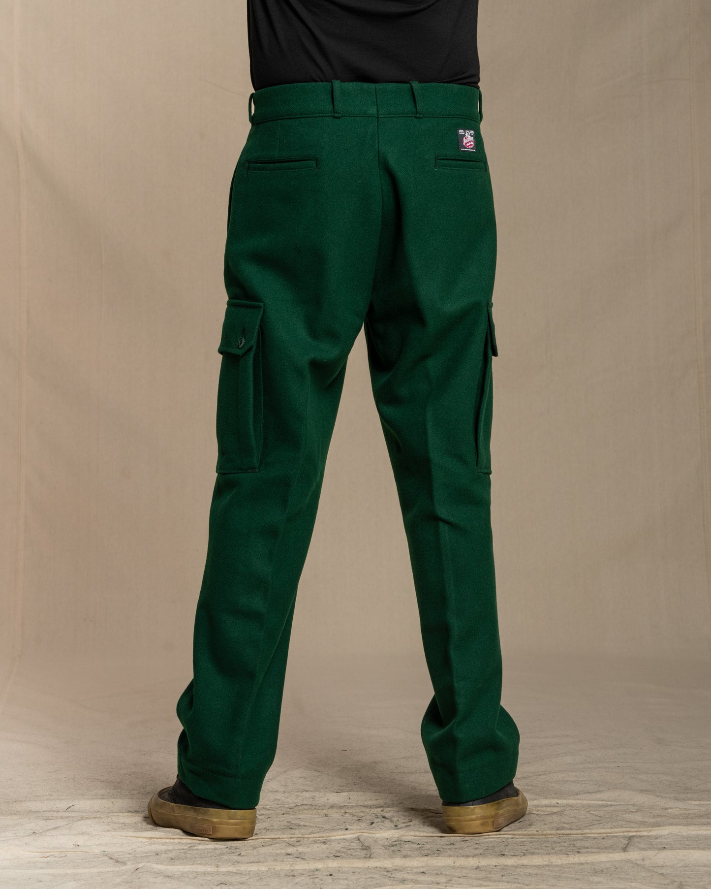 Green wool cargo pants worn by a person on a canvas background