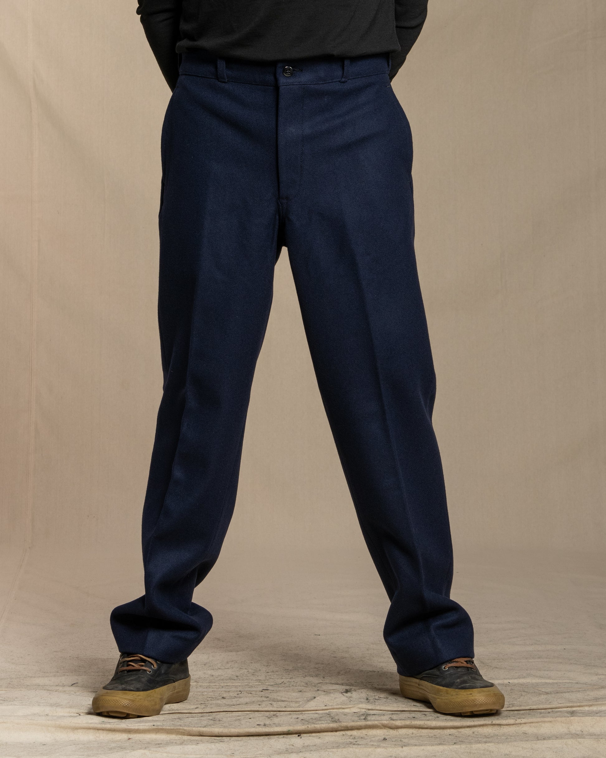 Navy blue wool pants worn by a person on a beige background