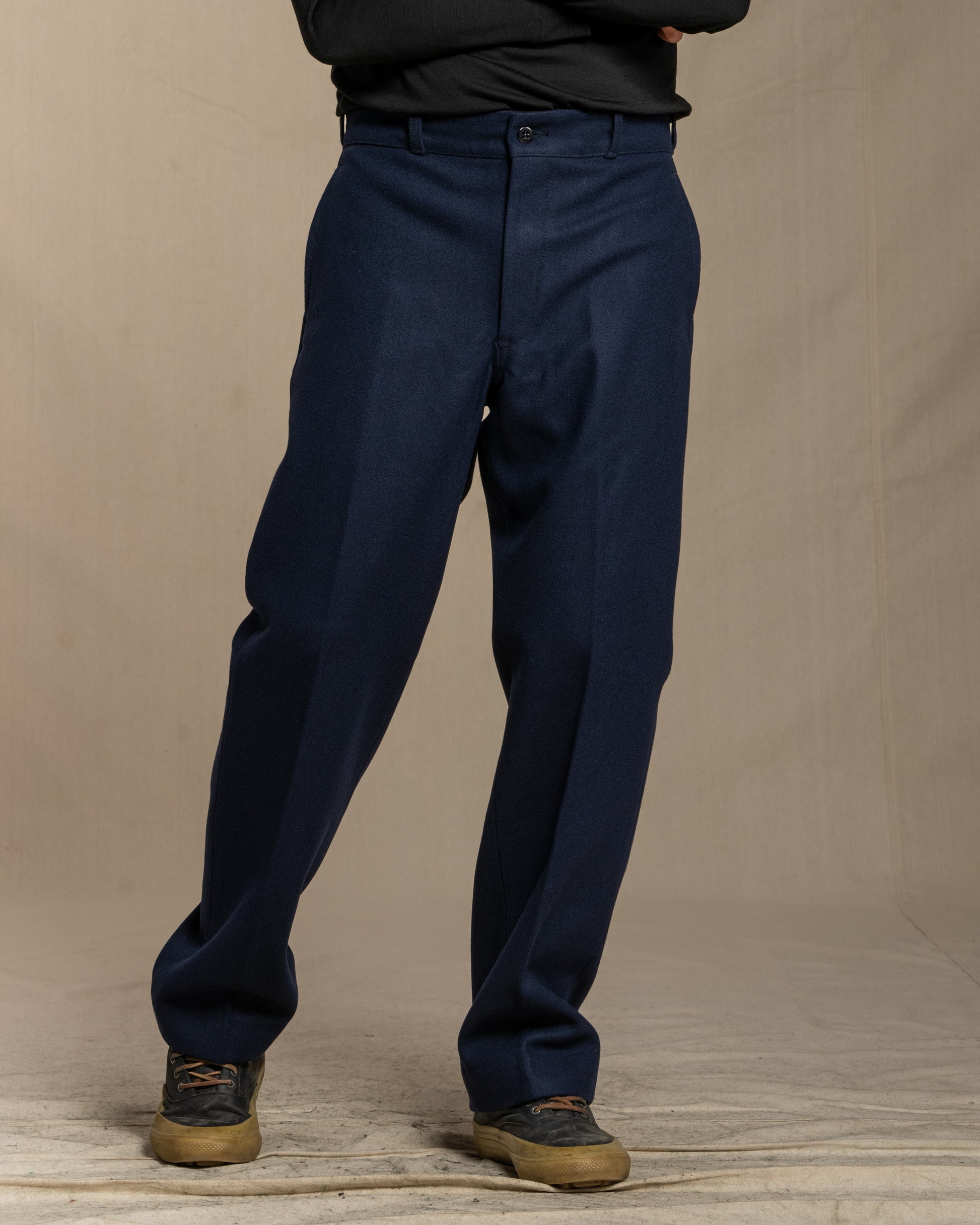 Navy blue wool pants worn by a person on a beige background