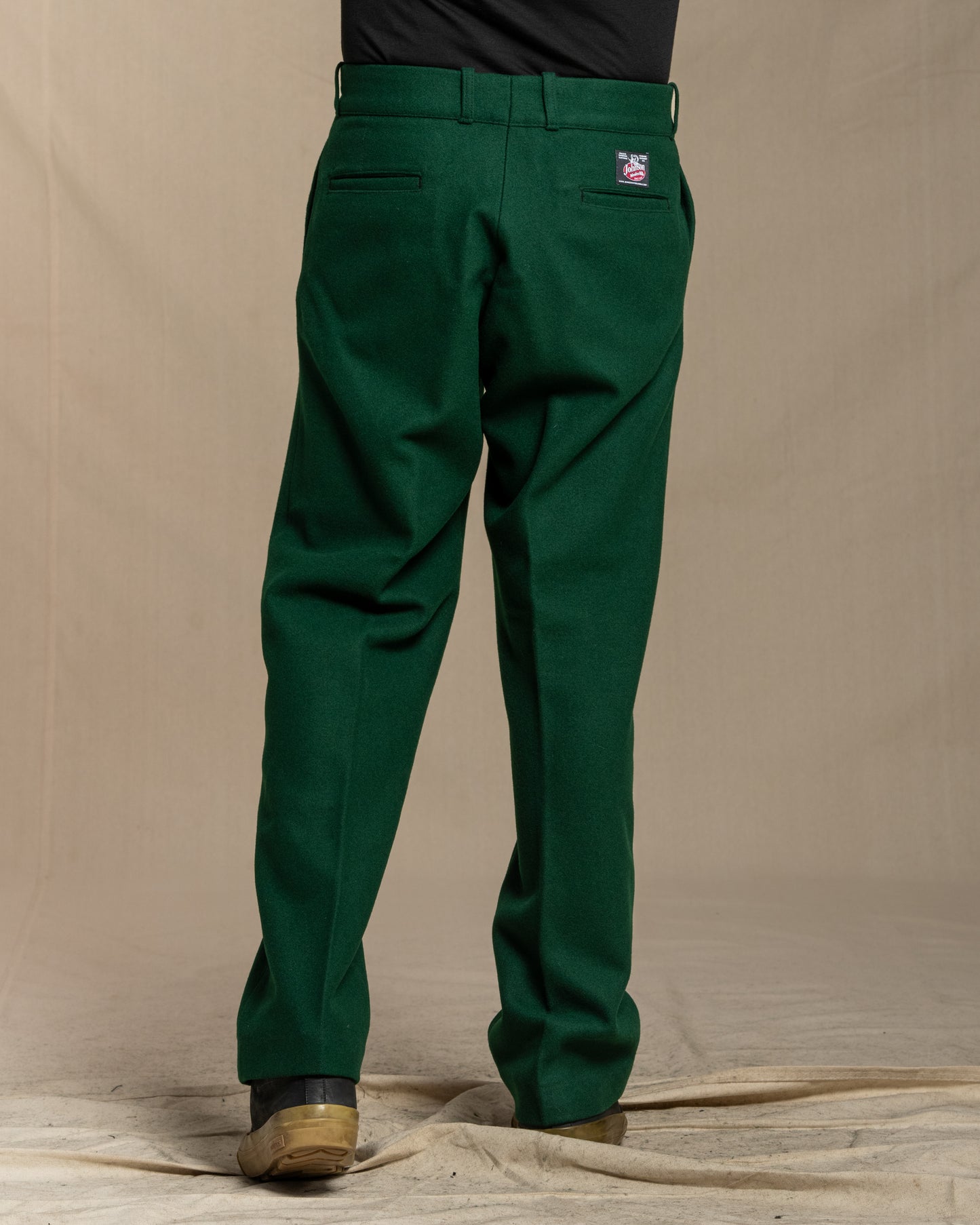 Green wool pants worn by a person on a canvas background