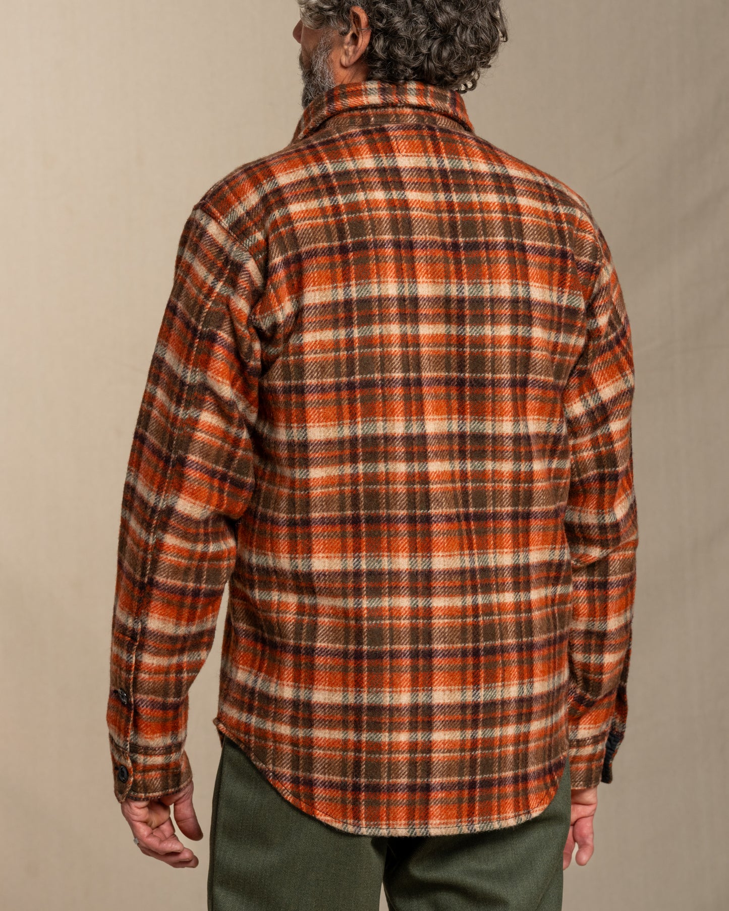 Person wearing a wool plaid shirt with a neutral background