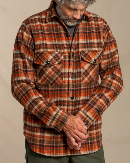 Man wearing a tan and brown plaid shirt against a beige background