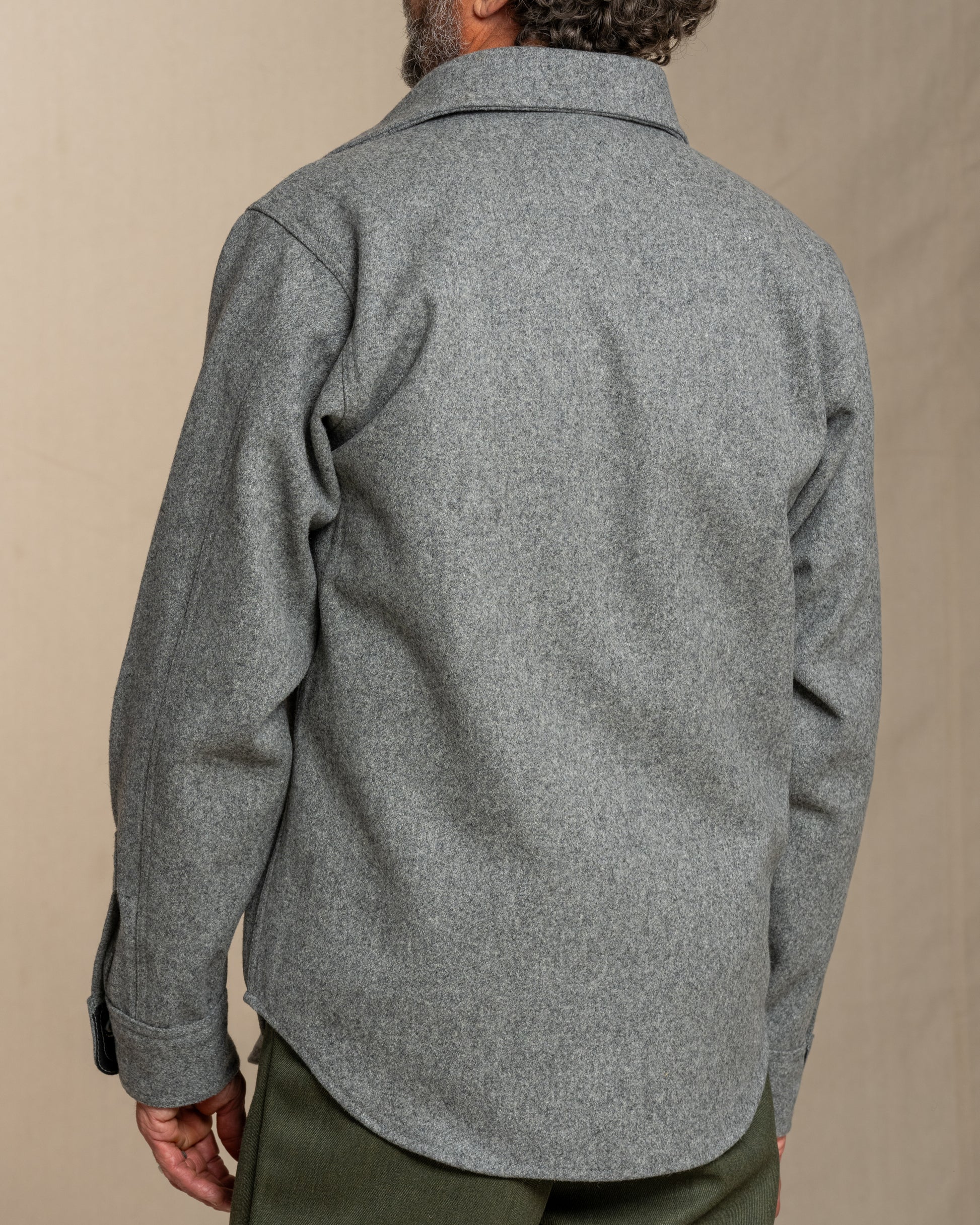 Person wearing a gray wool shirt on a beige background