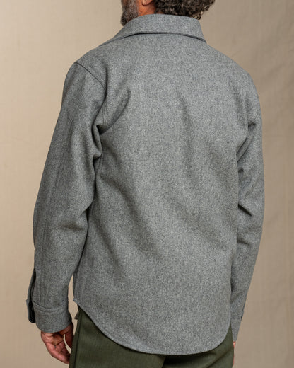 Person wearing a gray wool shirt on a beige background