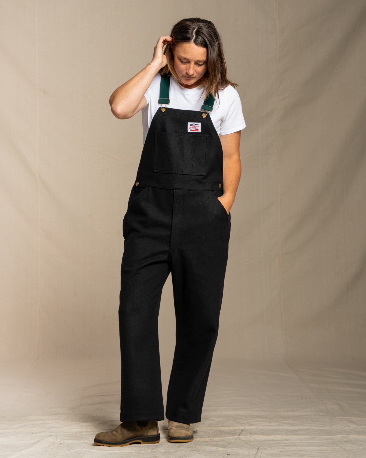 Person wearing wool black overalls with a beige background