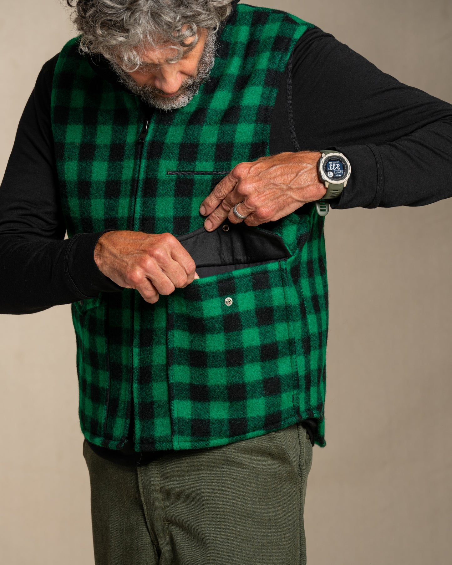 Man wearing a green checkered vest with a plain background