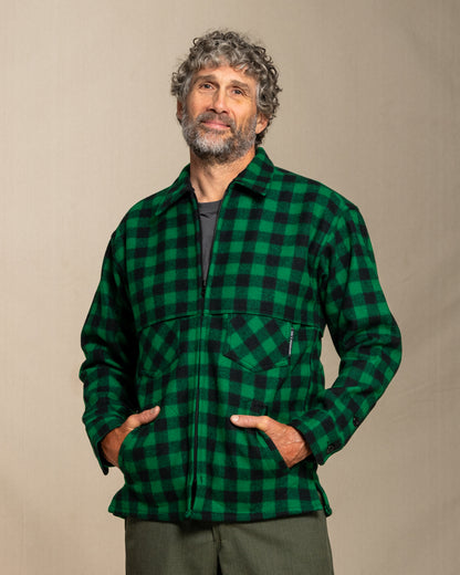 Man wearing a green and black wool checkered jacket against a beige background