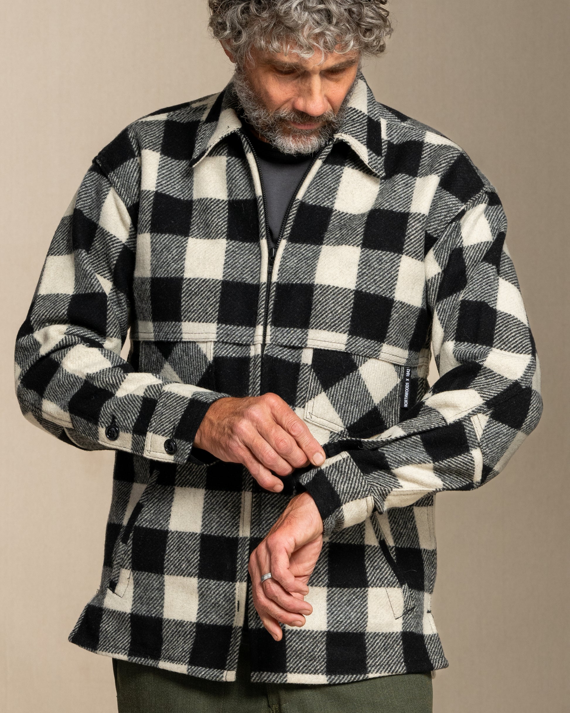 Man wearing a black and white checkered wool jacket against a beige background