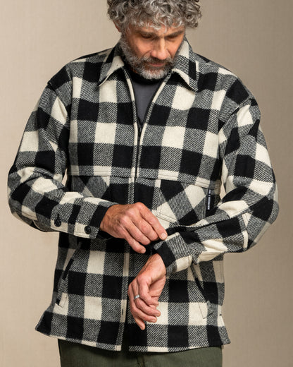 Man wearing a black and white checkered wool jacket against a beige background