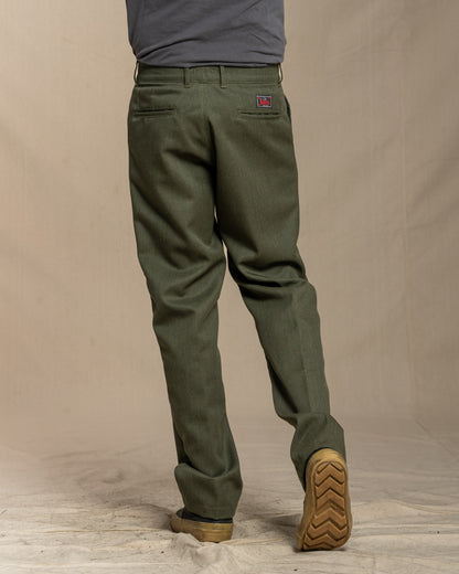 Person wearing green whipcord wool pants and brown boots on a beige background