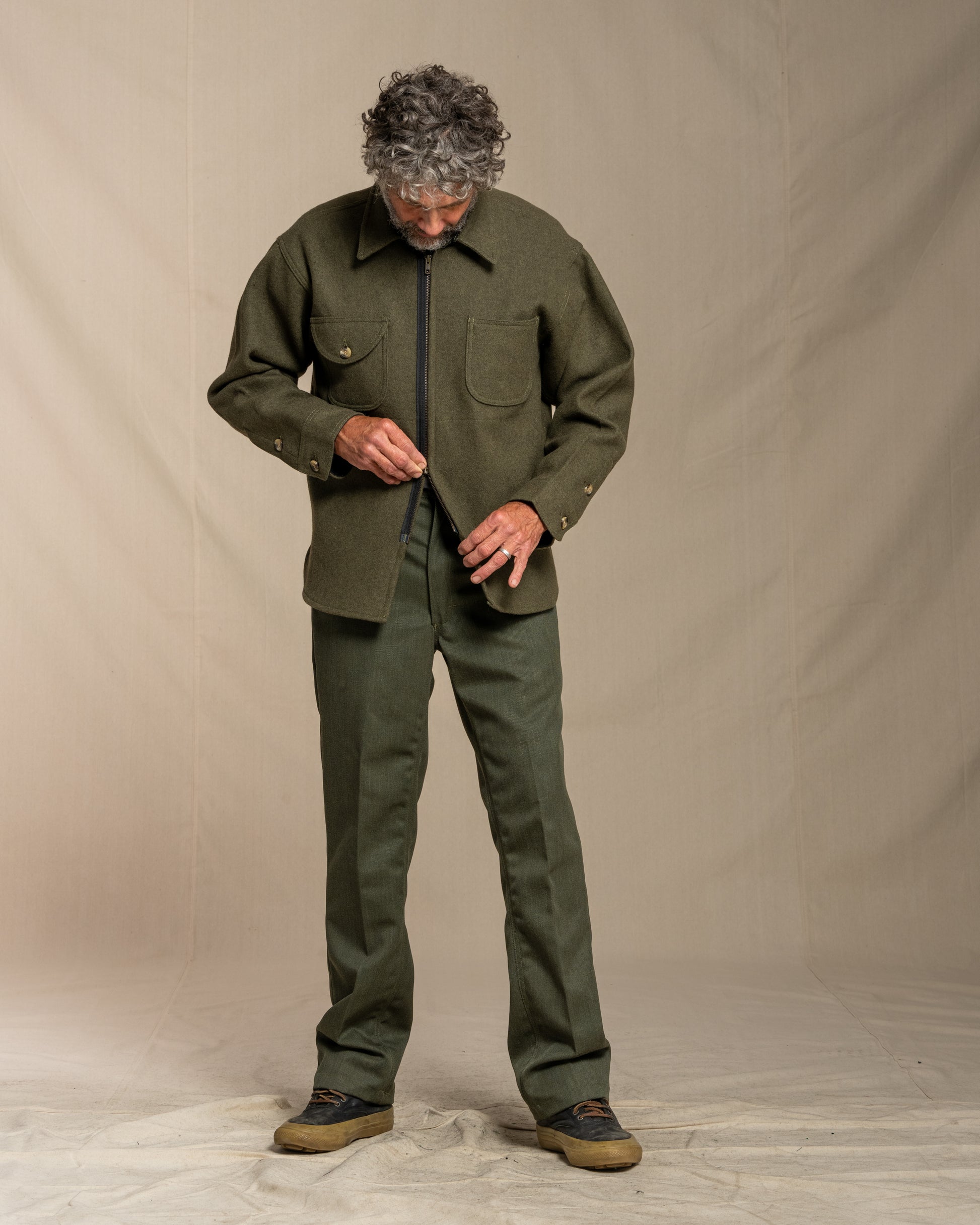 Man wearing a loden jacket against a beige background