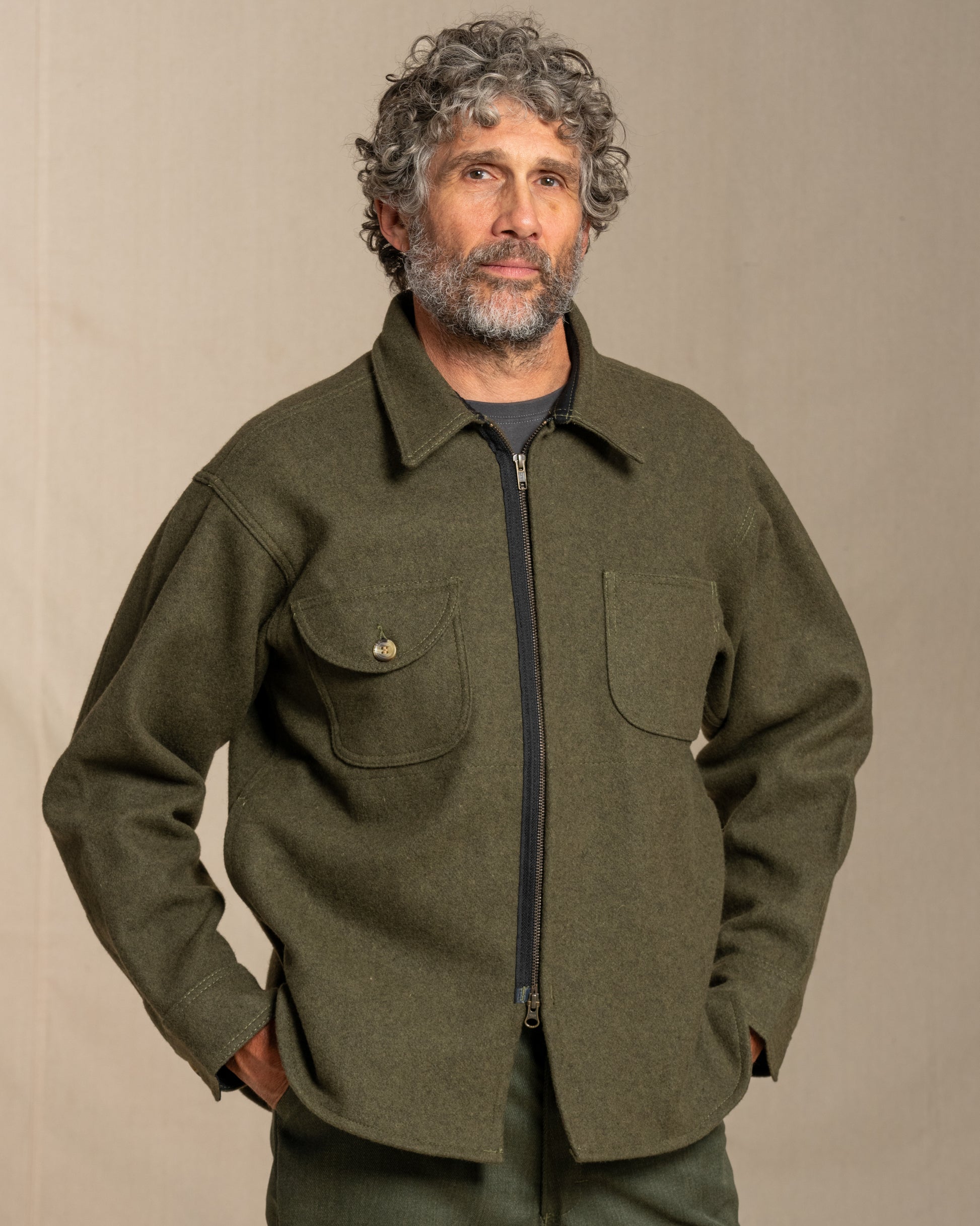 Man wearing a loden jacket against a beige background