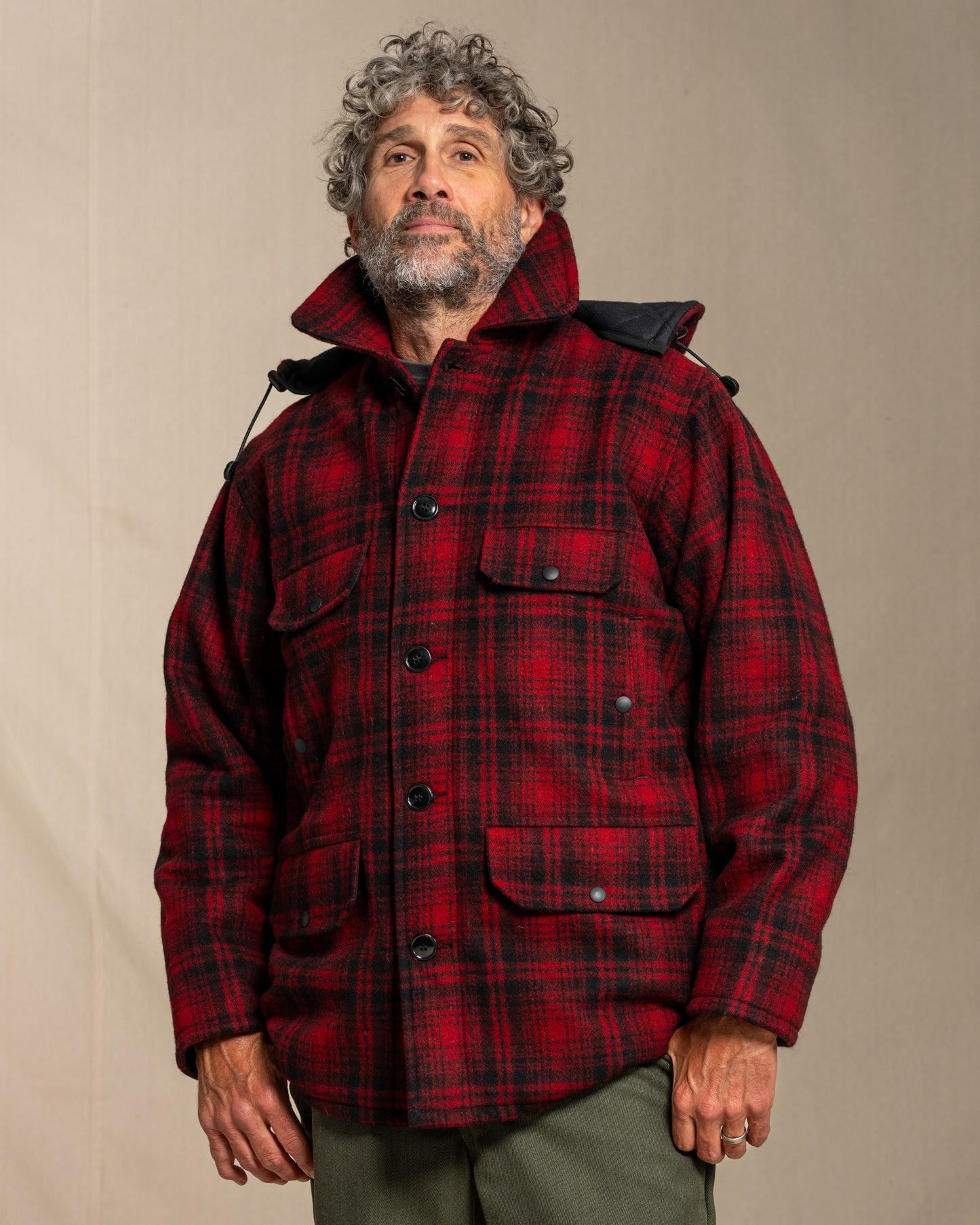 Man wearing a red plaid wool jacket against a beige background