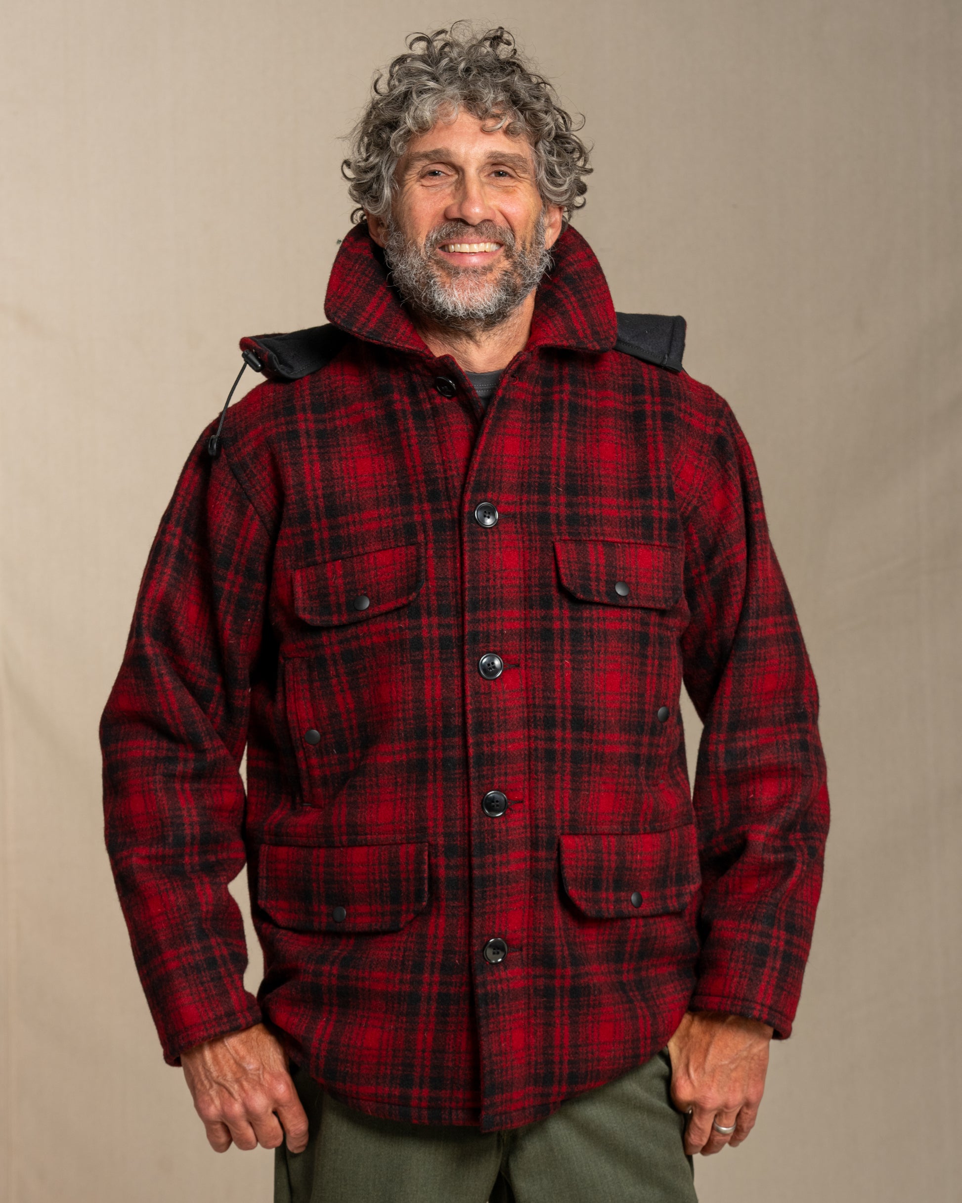 Man wearing a red plaid wool jacket against a beige background