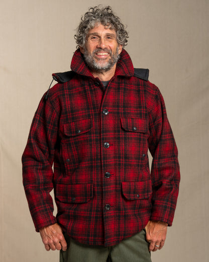 Man wearing a red plaid wool jacket against a beige background